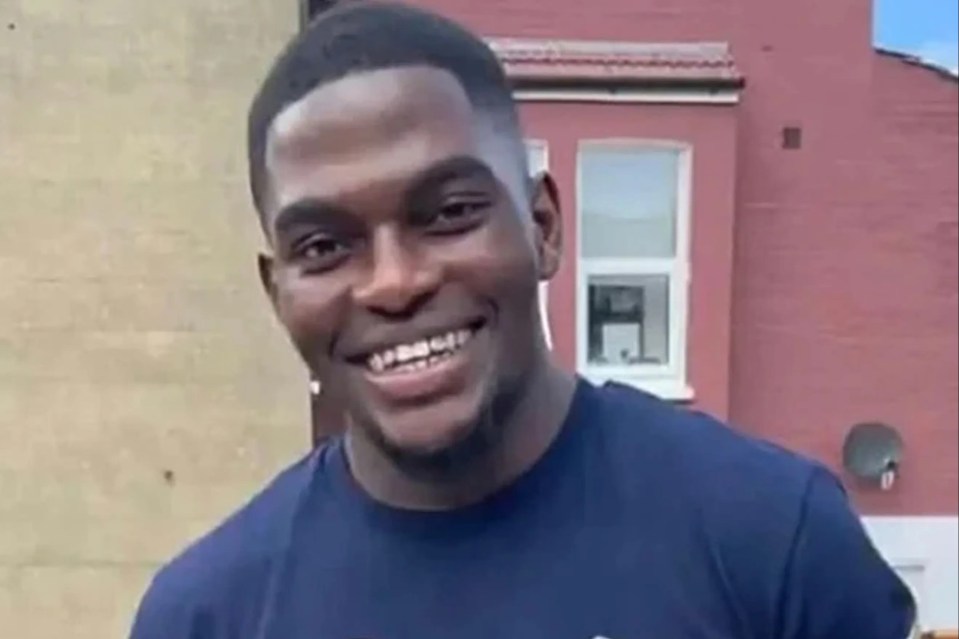 a man wearing a t-shirt that says `` i love money '' is smiling in front of a red building .