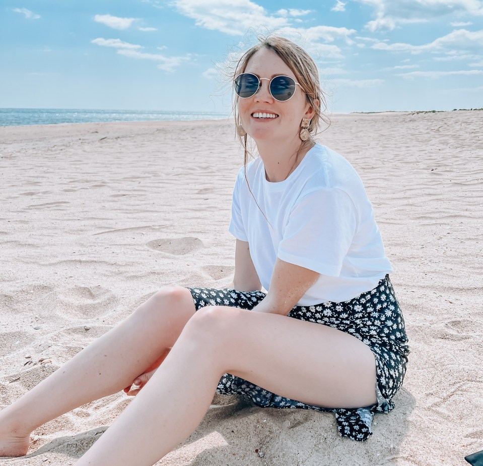 Woman sitting on a sandy beach.