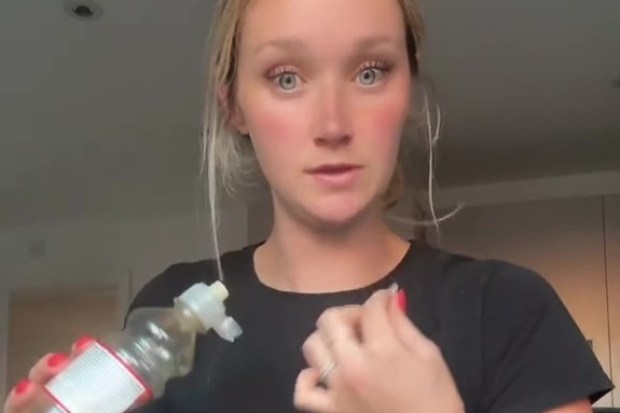 Woman holding a bottle of Tesco fruit drink, warning about choking hazard.